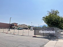 Parking lot pictured in August 2021. Fence reads "#BoulderStrong" Boulder King Soopers parking lot, August 2021.jpg