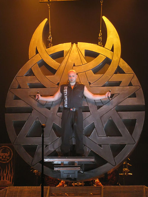 David Draiman on stage in front of the Believe logo