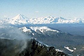 Vista do Dzenzourski coberto de neve do nordeste (centro);  em primeiro plano, a cratera Karymski e, em segundo plano, à esquerda, a Koriakski reconhecível pela sua forma cónica.