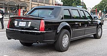 A black Cadillac limousine is at a 45-degree angle, showing to the camera its rear and starboard sides. The trunk sports two antennae, there is a presidential seal on the rear passenger door, and the license plate is numbered "800 002".