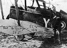 Malcolm McGregor, debout en uniforme à côté de son appareil, en 1918, regardant le photographe.