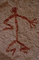 Humanoid stick figure painted on a rock wall in red. The figure is shown in Stylistic group C.
