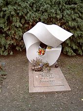 Tombe avec pierre tombale sculptée élaborée et dalle simple avec inscription.  Il y a des fleurs fraîches sur la tombe.