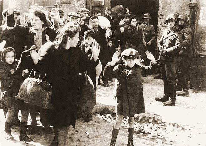 Insurrection du ghetto de Varsovie, avril-mai 1943.  Photographie extraite du rapport de mai 1943 de Jürgen Stroop à Himmler. Légende originale en allemand : « Poussés hors de leurs trous ».   Certaines des personnes visibles sur cette photo ont été identifiées :  – le petit garçon au premier plan est peut-être Artur Dab Siemiatek, Levi Zelinwarger (près de sa mère Chana Zelinwarger) ou Tsvi Nussbaum ; – Hanka Lamet, la petite fille à gauche ;  – Matylda Lamet Goldfinger, la mère de Hanka, deuxième en partant de la gauche ;  – Leo Kartuziński, en arrière-plan avec un sac blanc sur l'épaule ;  – Golda Stavarowski, la première femme à droite, au fond, qui ne lève qu’une main ;  – Josef Blösche, le SS avec un pistolet-mitrailleur à droite, exécuté en 1969.