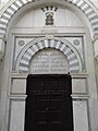 A mausoleum door, topped by a commemorative inscription.