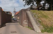 Vue de la rue Vissersdijk avec porte de la ville et l'église catholique à Woudrichem