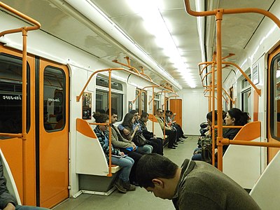 Интерьер головного вагона 81-717М в оранжевой окраске, модернизированного в Тбилиси. Сиденья имеют раздельные спинки и сидушки и дополнительные поручни по бокам, светильники прямоугольные