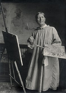 Anna Ancher med kittel, palet og pensler. 1911.jpg