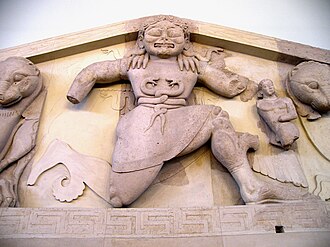 The archaic Gorgon at the pediment of the Temple of Artemis as shown at the Archaeological Museum of Corfu. She wears a belt of intertwined snakes, a fertility symbol. Close up of Gorgon at the pediment of Artemis temple in Corfu.jpg