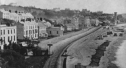 Ligne du South Devon à Dawlish (Devon) vers 1870. À cette époque, la conduite d'aspiration (tube à vide) a été démontée, mais on distingue l'écartement large de la voie et la tour carrée de la station de pompage, au fond.