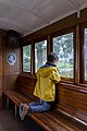Image 44Gabriel looking outside the window of a narrow-gauge train coach, Mariefred station, Eastern Södermanland Railway Museum, Sweden