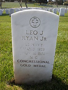 Una lápida de color blanco se encuentra en medio de un cementerio.  "Leo J. Ryan Jr" está grabado en él.