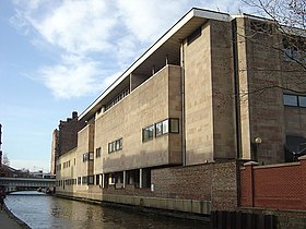 Low level view of a light coloured building alongside a canal