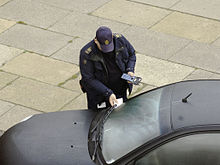 A parking enforcement officer issuing a ticket to a vehicle in Copenhagen, Denmark Parking fine in Copenhagen.jpg