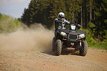 ATV im Drift auf Schotter. Die volle Körpergewichtsverlagerung spielt eine besondere Rolle, will man dem Umkippen eines solchen Fahrzeugs entgegenwirken. Nur mit dieser Verlagerung bleibt es sicher in der Kurve manövrierbar.