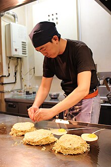 A man making an okonomiyaki at a restaurant in Hiroshima Preparing okonomiyaki in Hiroshima.jpg