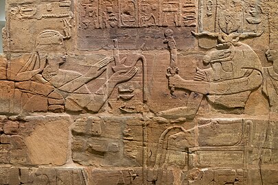 Zid iz peščenjaka, na katerem Aspelta daruje Maat (Resnica), bogu z ovnovimi rogovi Amon-Raju v spremstvu Anuket; Tempelj T v Kavi, Sudan, zdaj v Ashmolovem muzeju (I9J2.I295)[7]