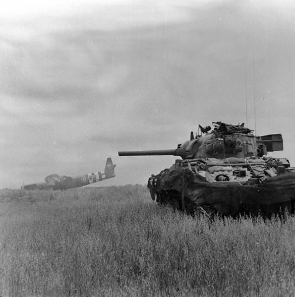 A Sherman DD amphibious tank of 13th/18th Royal Hussars in action against German troops using crashed Airspeed Horsa gliders as cover near Ranville, O