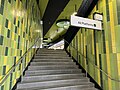 The stairs leading up to the mid-level concourse taken from the main concourse, with green tile works around the walls, July 2024