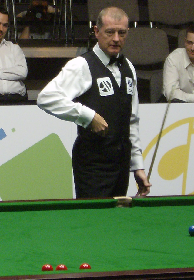 Steve Davis holding his cue stick, standing behind a snooker table