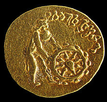 The Tillya Tepe Buddhist coin, with a naked deity wearing chlamys cape and petasus hat pushing the Wheel of the Law. Kabul Museum. This is "most probably Buddha Sakyamuni in a yet non-canonical representation". Tilia Tepe gold token. Kabub Museum.jpg