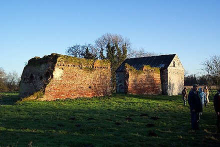 The ruins of Woking Palace in 2004. The stone building on the right is an original part of the palace, but the brick walls to the left are the remains of a 16th-century barn.[345]