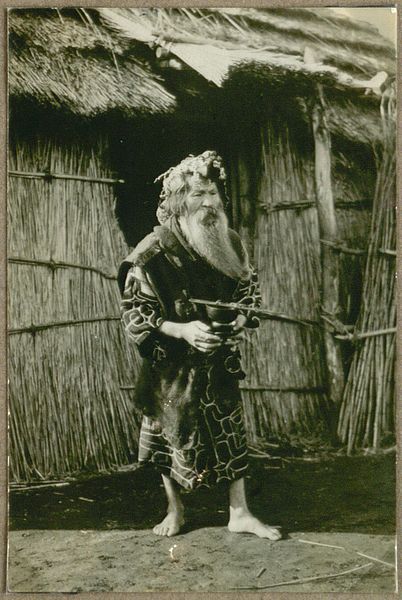 File:Aino outside his house; in his hand, he is holding ceremonial eating (drinking?) tools. (10795478385).jpg