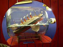 Imagen de un modelo en miniatura del Titanic en el interior de una botella de cristal, en reminiscencia al hundimiento del mismo tras chocar con el iceberg.