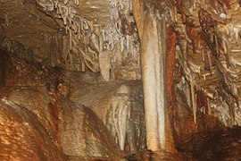 Several Stalactites hanging from the ceiling and a large column