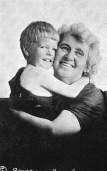 An older white woman, smiling, embracing a small child with blond hair.