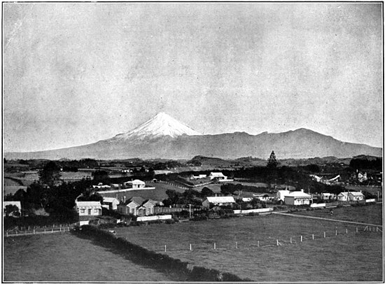 Settlement with several houses spread out along roads, with Mount Egmont (Taranaki) in the background