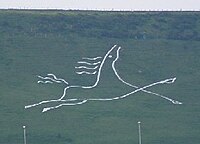 A stylised figure of a galloping white horse. Folkestone White Horse on Cheriton Hill, Folkestone