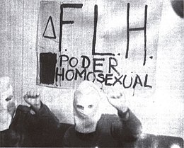 Deux membres du Frente de Liberación Homosexual posent encagoulés et le poing levé devant une banderola "FLH. Poder homosexual". 1972.