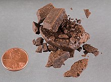[1] ein angebrochenes Stück gepressten Haschischs mit einer US-amerikanischen 1-Cent-Münze zum Größenvergleich;
unretuschierte Originalaufnahme von der DEA, auf Commons hochgeladen von Benutzer Fred J am 12. Juni 2005, danach mehrmals retuschiert
