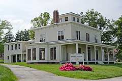 A square white house with a porch in front and an added ell behind. A sign in front reads "Hillside" in large letters and "John B. Gough" in smaller letters.