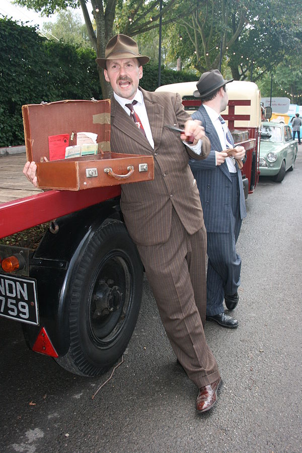 An actor performing the role of a spiv selling goods "from the back of a lorry" at a 2011 historical re-enactment, complete with a look-out watching f