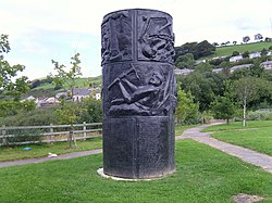 Large circular metal memorial, with miners shown in relief on the sides. The memorial also has lists of names at the bottom.