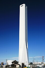 白くてシンプルなデザインの塔です。一番高い所に四角くて横長の窓が開いています。足元に昭和モダン建築の民家があるため、キン未来ふうのタワーとの対比が面白いことになっています。