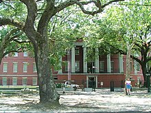 The Ionic-columned portico of the New Orleans Mint building's façade in June 2005, seen from across Esplanade Avenue. The trees along the street in front of the Mint have grown tall, such that it is very difficult to obtain a good photograph of the old mint's façade today.