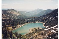 Lago alpino situado em uma bacia entre montanhas nevadas