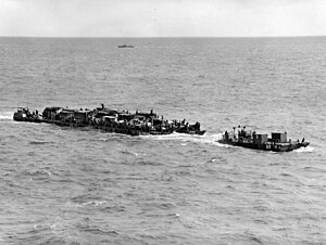 Loaded Rhino ferry towed by a "Rhino tug" approaches a Normandy invasion beach on D-Day Rhino ferry RHF-3 approaches Normandy beaches 6 June 1944.jpg