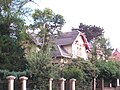 Residential house in half-open development (forms a semi-detached house with No. 57), with enclosure and front garden