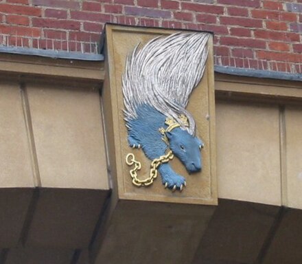 Heraldic emblem of Sidney Sussex College, a porcupine (statant) azure quills collar and chain or, being the crest of the Sidney family[11][12]
