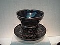 A Song Dynasty stoneware tea bowl resting on a Ming Dynasty stand
