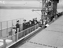 King George VI on the bridge, on his left is the Captain of HMS Archer and Admiral Commanding Aircraft Carriers, Admiral Lyster.