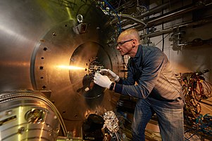 AEgIS technical coordinator Stefan Haider in front of the main apparatus. The part removed is amongst colleagues called the "Sun" as it has several instruments sticking out from the central circular flange. Aegis1.jpg