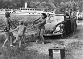 Propagandabilde fra Kraft durch Freude 1939 som viser aktiv og sunn fritid med strandtur, passasjerdamper, radioapparat og KdF-Wagen. Bilen fikk snart navnet «folkevogn». Volkswagen Type 1 ble utviklet av Ferdinand Porsche, lansert 1938 og betalt gjennom forskudd. Produksjonen ble hemmet av andre verdenskrig og kom i gang først etter krigen.[2]