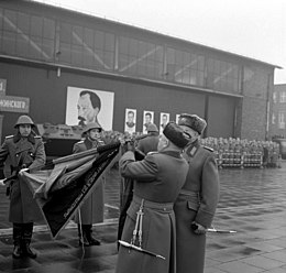 Erich Mielke (2. right) attaches the band name to the troops of the guards regiment flag Bundesarchiv Bild 183-F1215-0028-001, Berlin, Namensverleihung an Wachregiment.jpg