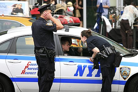 New York City Police Department (NYPD) officers conversing with other officers in a police car