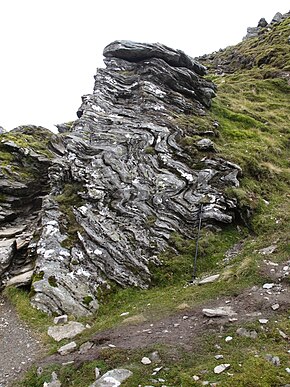 Folded Dalradian phyllites of the Ordovician Ben Ledi Grit Formation, part of the Southern Highland Group of the Dalradian Supergroup just below the summit of Ben Lomond - walking pole about 1.2 m long for scale Folded Dalradian phyllites.JPG